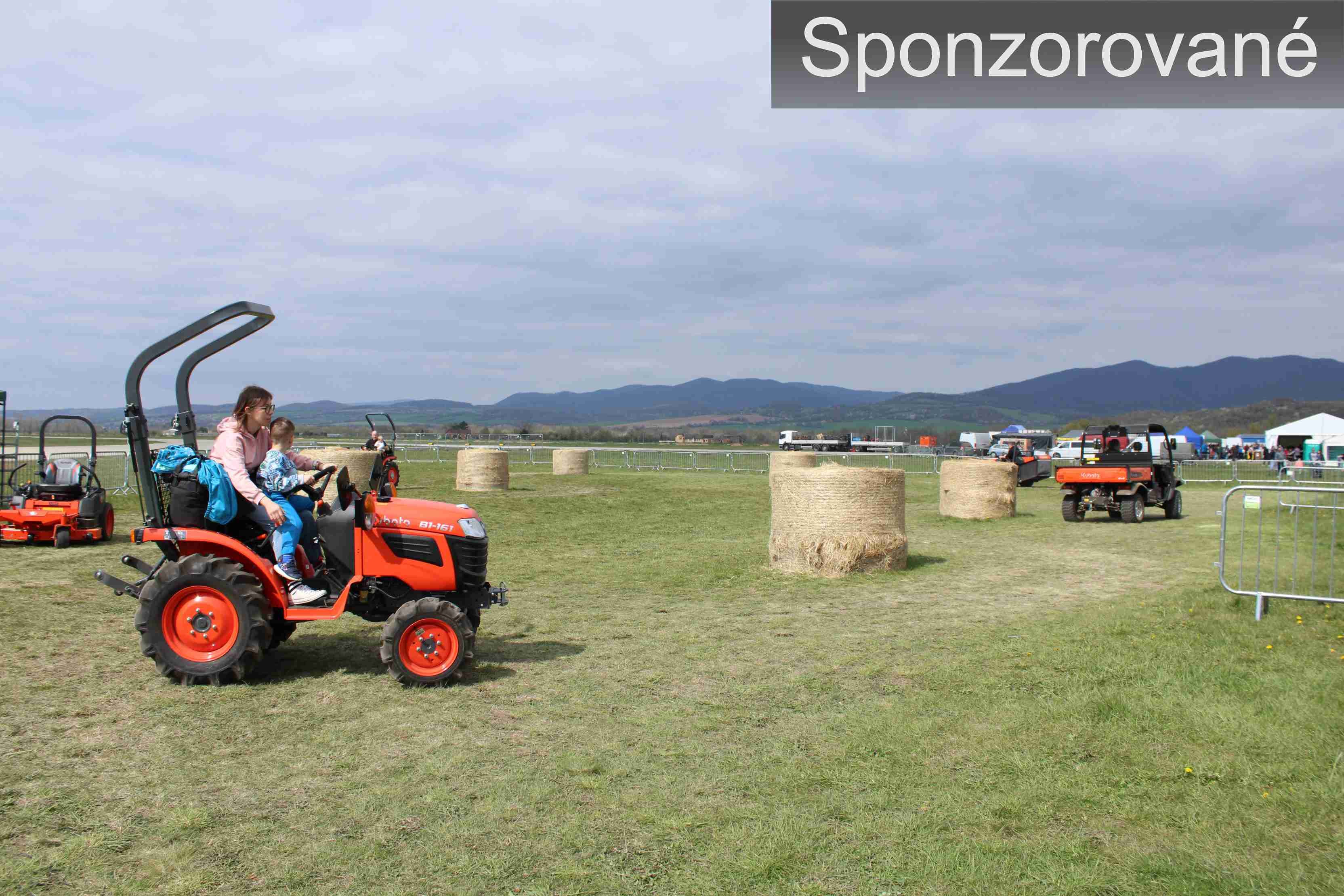 Matka s dieťaťom jazdiaci na traktore Kubota na zá